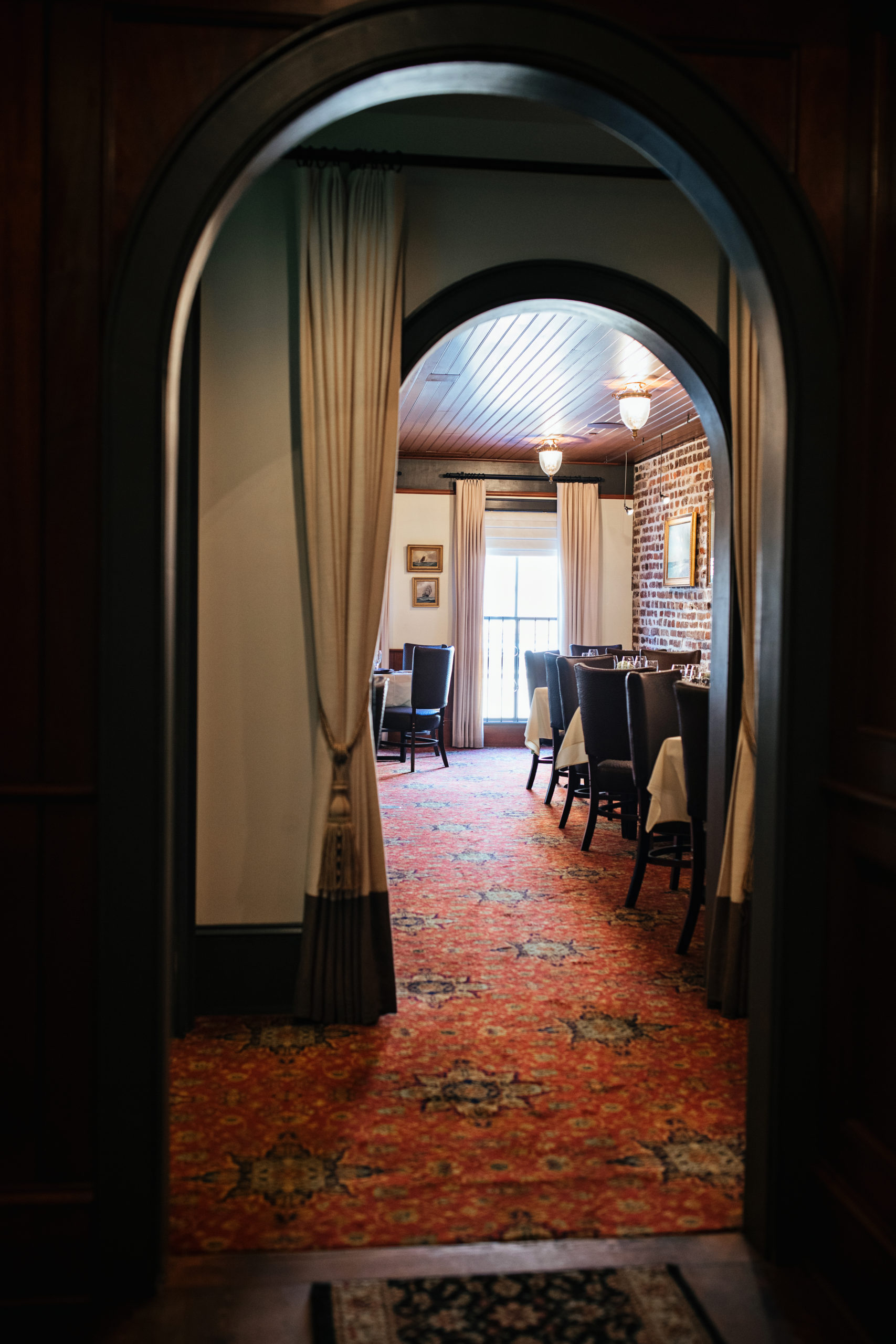 Arched hallway leaving to a restaurant dining room with exposed brick wall