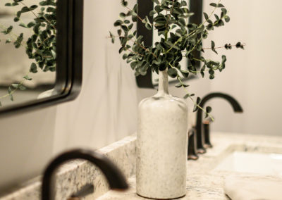 white vase with greenery on a bathroom counter