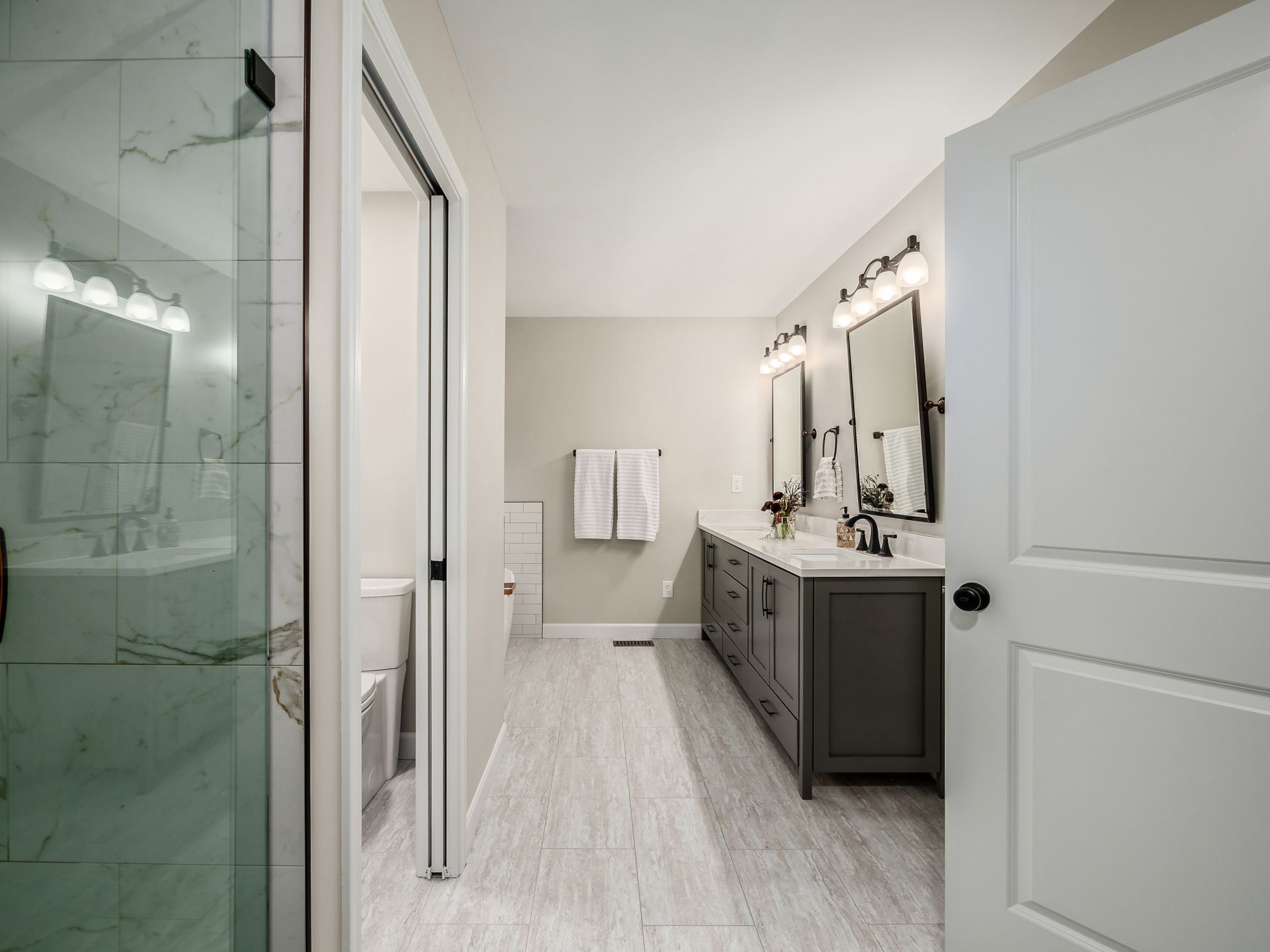 grey bathroom vanity, dark fixtures, soaking tub