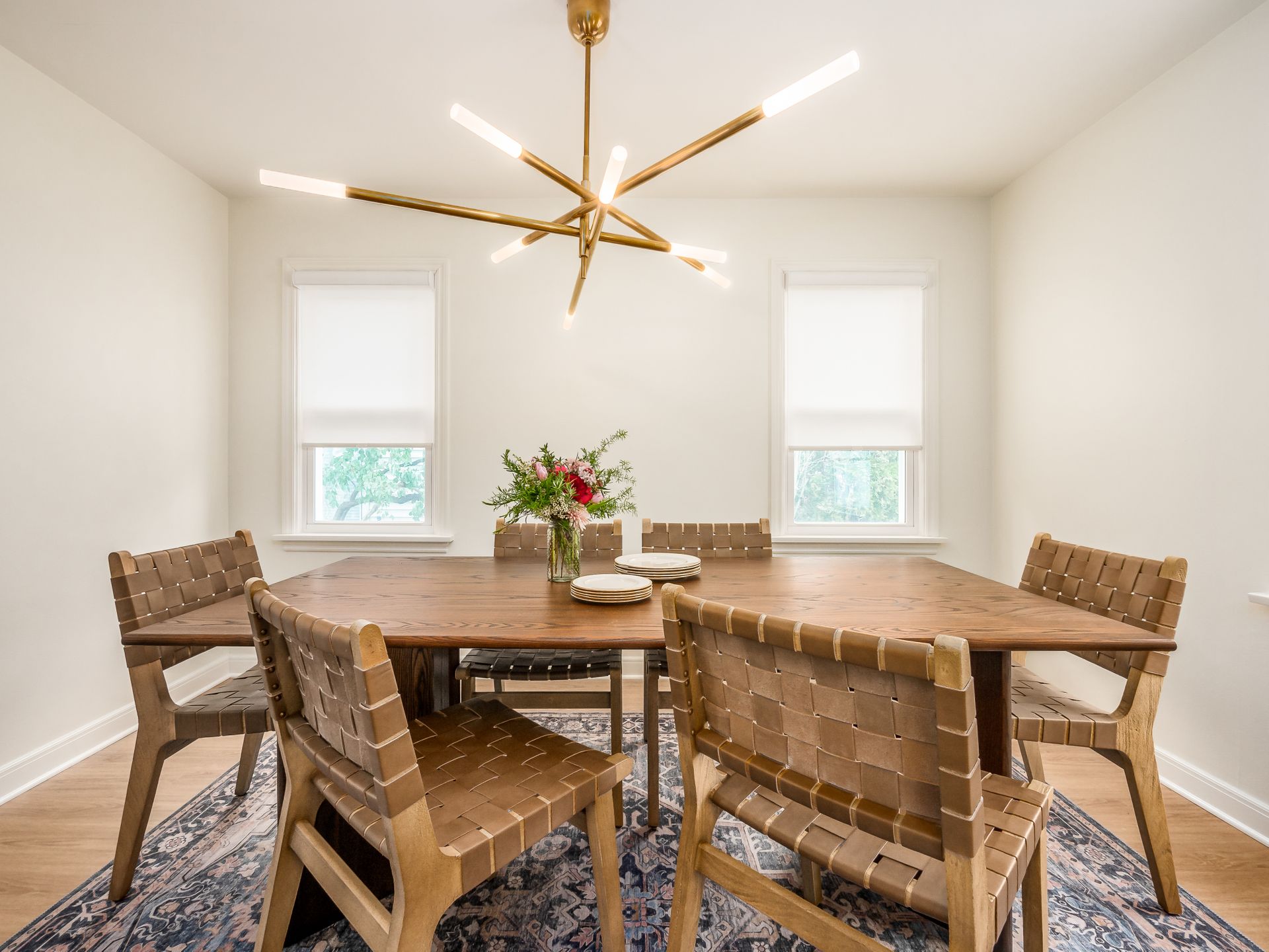 dining table with woven leather back chairs and brass light fixture
