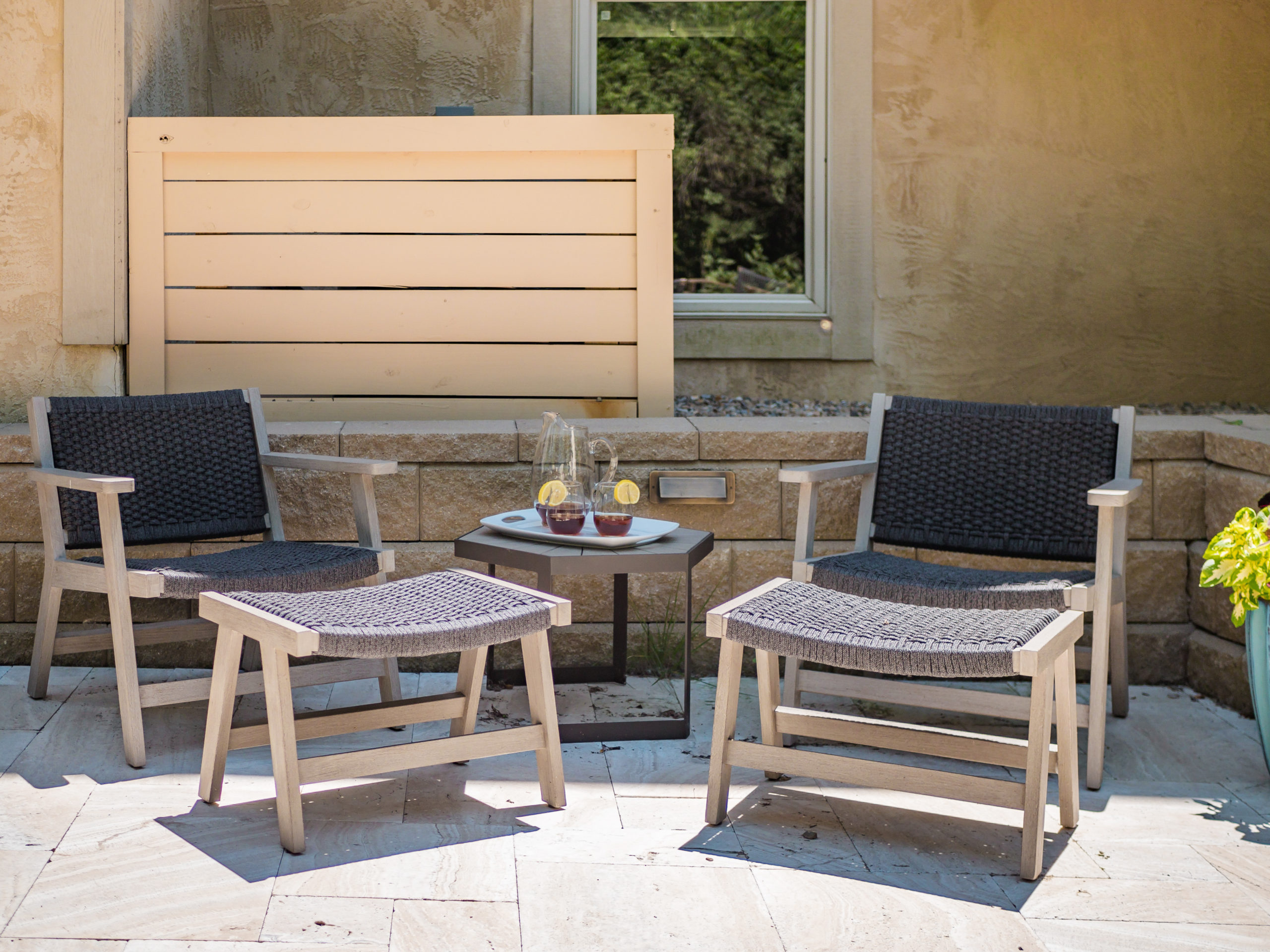 Modern outdoor patio seating with chairs, ottomans, and table