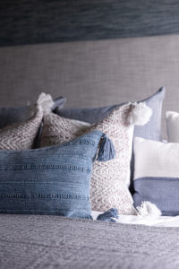 Blue, gray and tan throw pillows on bed