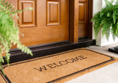 warm wood front door with welcome mat
