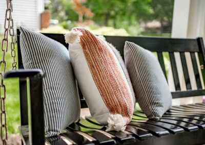 black front porch swing decorated with orange and gray throw pillows